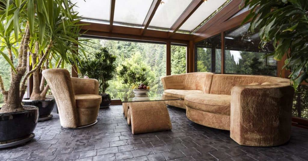canapé, fauteuil et table sous une véranda avec toit coulissant 