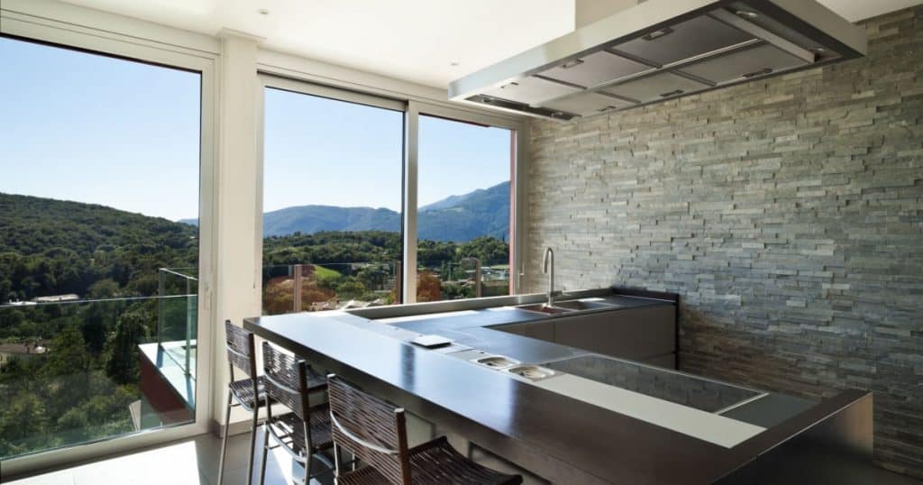 Une cuisine moderne installée dans une véranda, avec une vue sur les montagnes. 