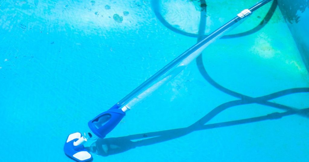 Aspirateur bleu dans une piscine, raccordé avec un tuyau flottant.