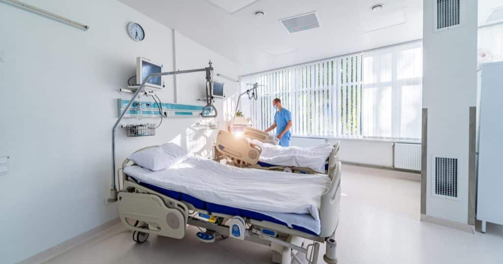 chambre d'hopital à deux lits (chambre double) avec un infirmier réglant un lit médicalisé