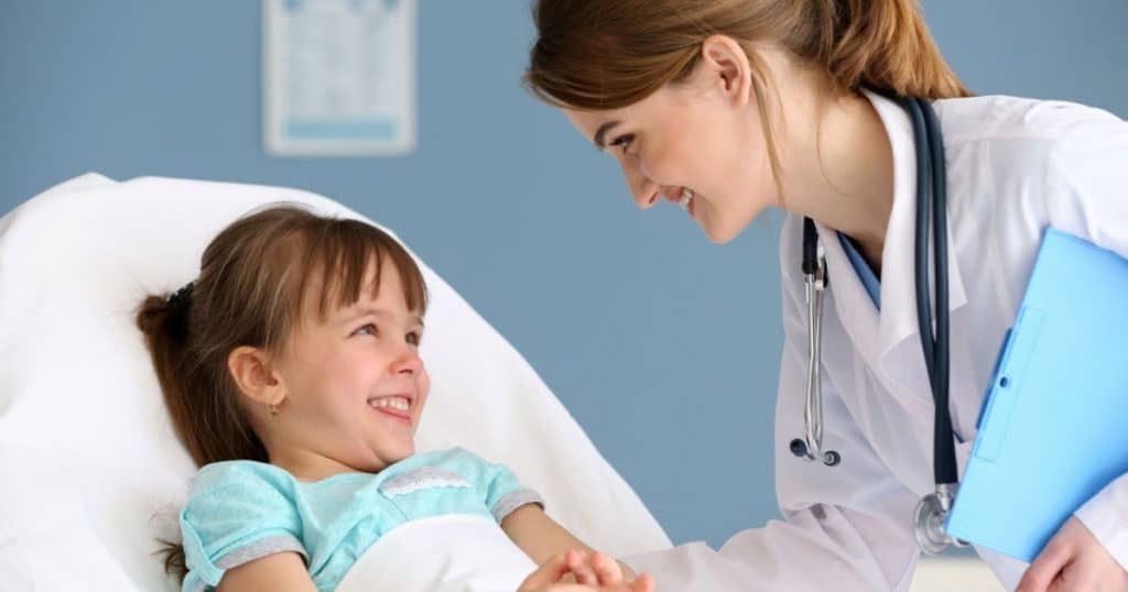 petite fille sur un lit d'hopital qui se fait soigner par une medecin en blouse blanche