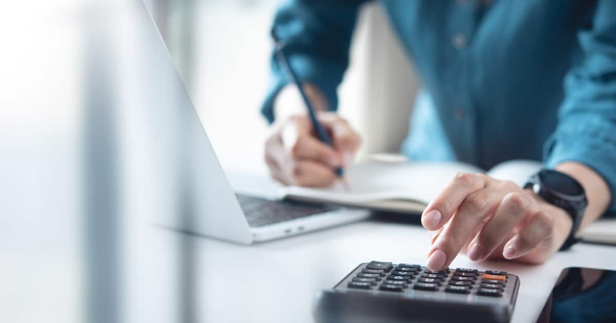 Une personne utilisant une calculatrice et prenant des notes en même temps.