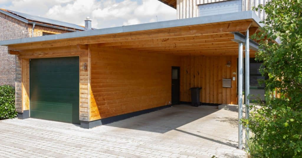 carport en bois semi-fermé par un garage dans une allée de maison