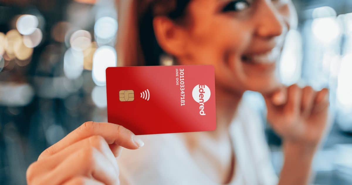 femme dans un open space en train de poser avec sa carte électronique Edenred pour chèques repas