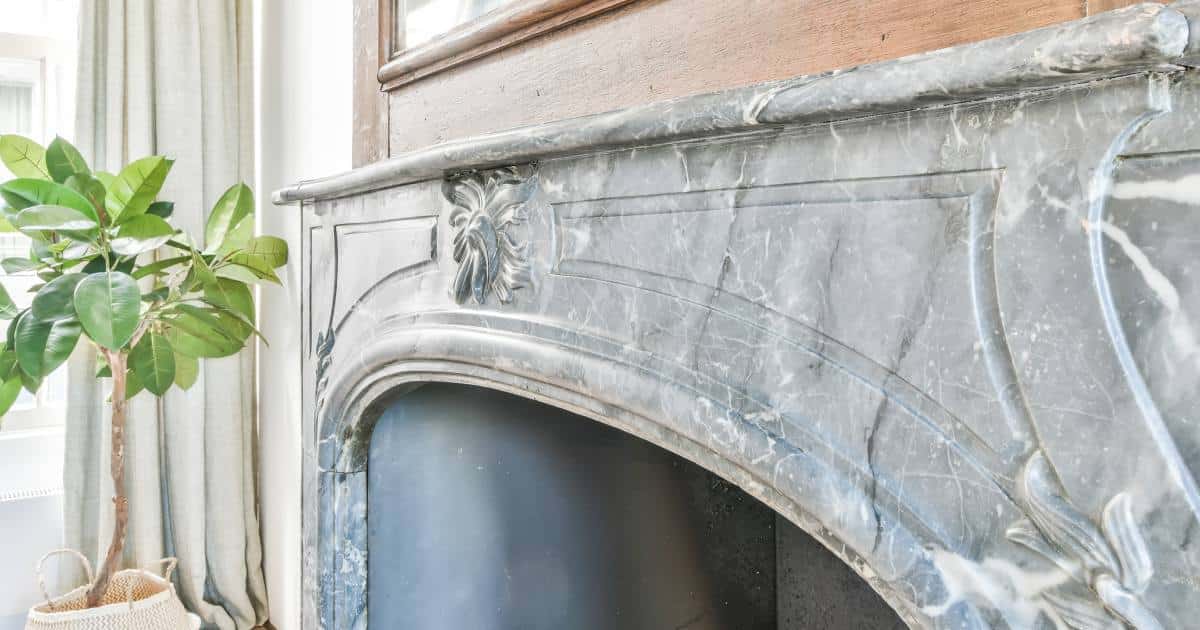Une cheminée en marbre gris dans le salon d'une habitation en Belgique.