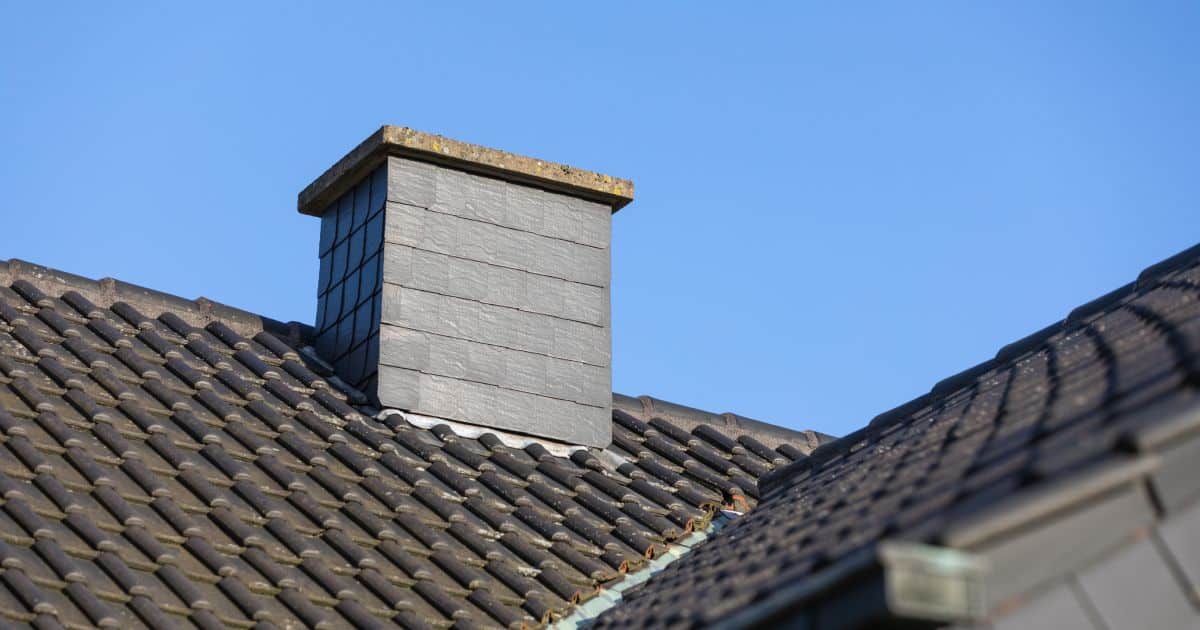 Cheminée recouverte d'ardoises sur un toit d'une habitation moderne.