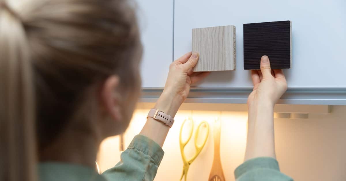 Femme choisissant la couleur et le matériau pour ses nouveaux meubles de cuisine à l'aide d'échantillon