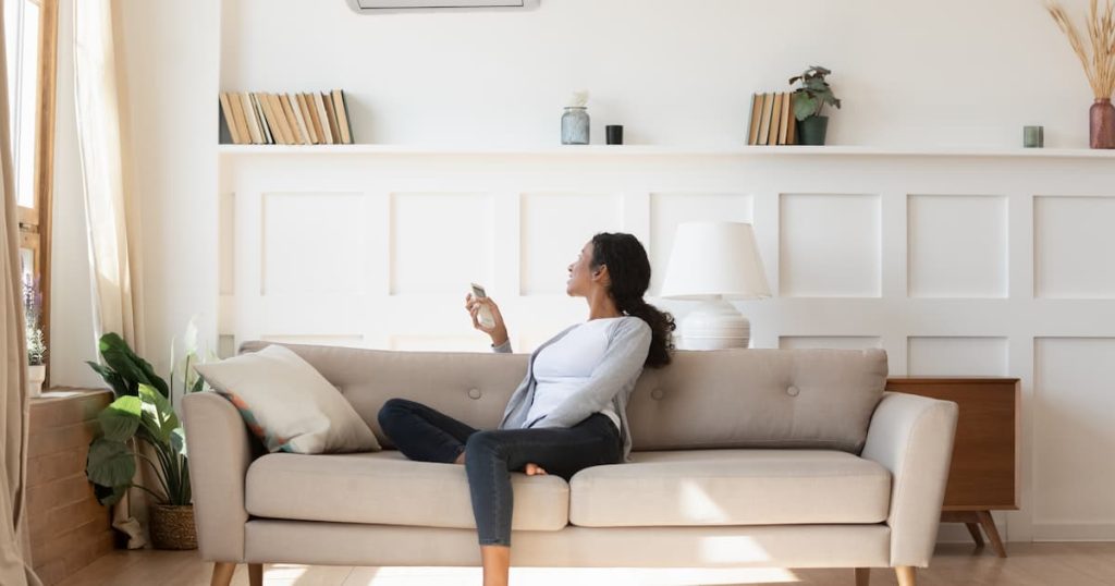 Femme en train de régler la température d'un air conditionné dans son salon