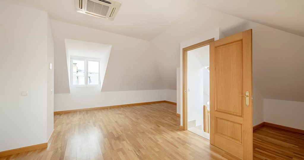Chambre spacieuse au sous-sol mansardée d'une maison individuelle avec lucarnes, parquet en chêne, climatisation au plafond et radiateurs en aluminium