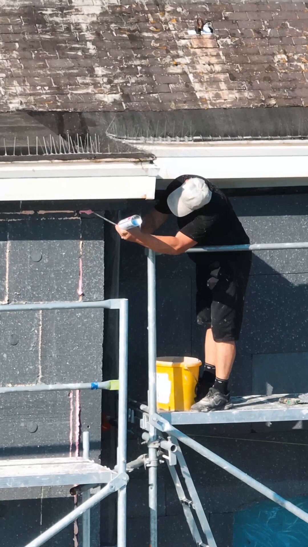 ouvrier qui colle un panneau isolant EPS sur une façade