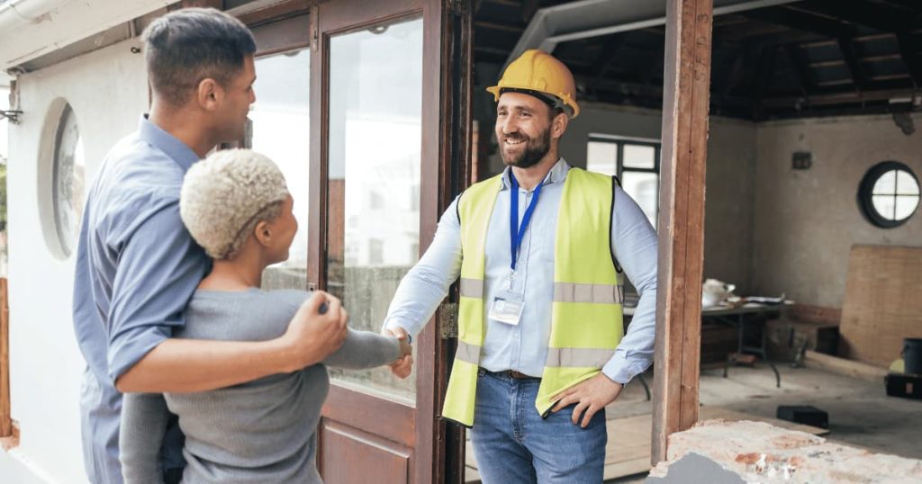 un constructeur serre la main à un couple qu'il aide