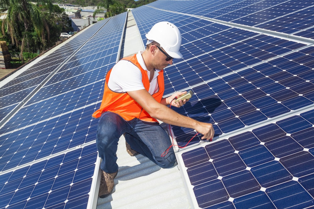 un ouvrier contrôle le bon fonctionnement des panneaux solaires posés sur le toit d'un bâtiment 