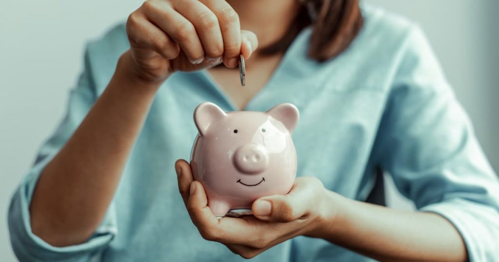 femme tenant une tirelire cochon et une pièce de monnaie