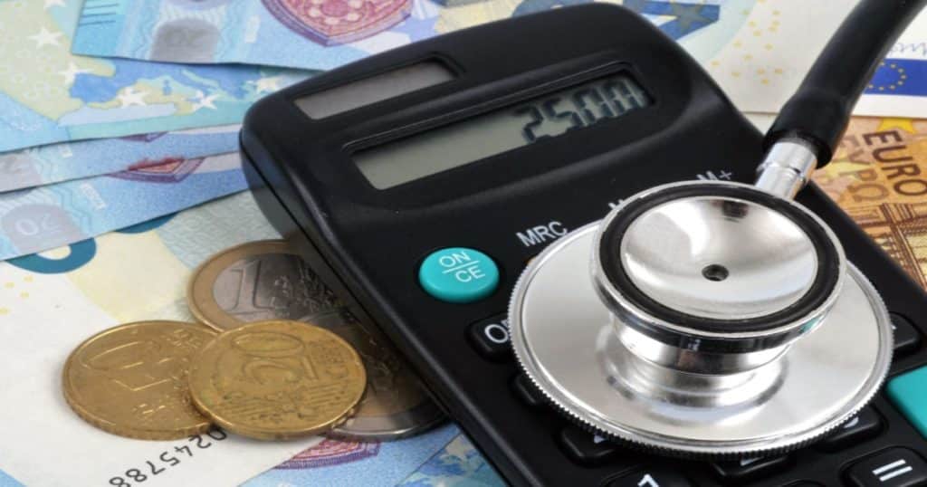 Un stéthoscope est posé sur une calculatrice autour de pièces et billets de monnaie. 