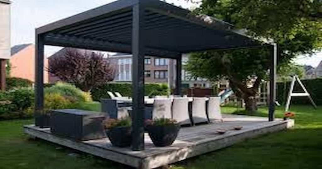 Terrasse au milieu d'un jardin avec table et chaises couvertes par une couverture de terrasse à lames orientables