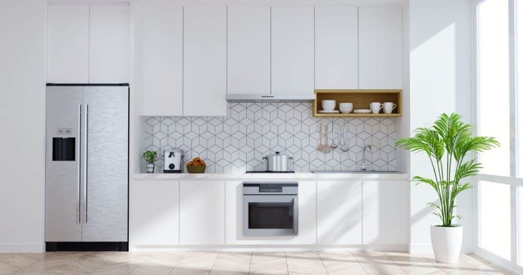 Cuisine aux couleurs neutres et claires : blanc, beige. Avec une plante.