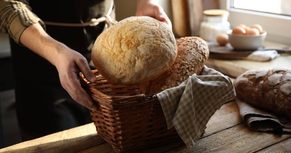 Panier à pain en osier avec personne déposant des pains dedans