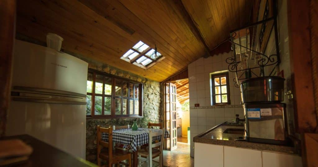 Petite cuisine de campagne au style rustique et robuste, murs en pierre et plafond en bois
