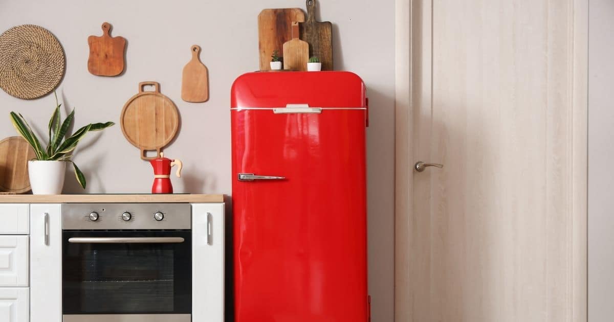 Cuisine rétro avec frigo rouge arrondi, vieux four et murs clairs