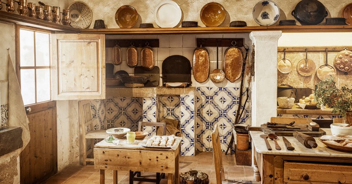 Cuisine de style cottage avec table en bois, céramiques sur les murs, ustensiles en fonte.