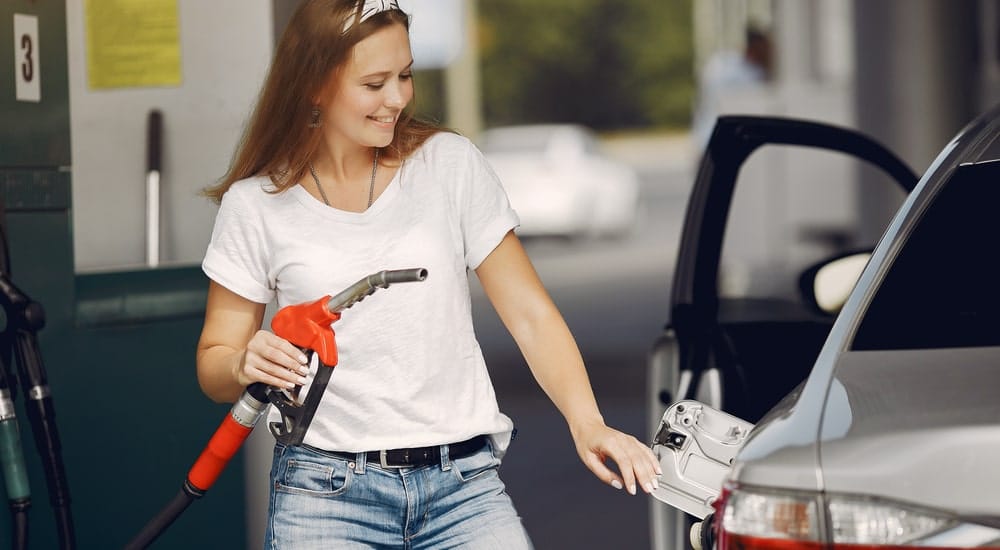 Une dame qui met de l'essence avec sa carte carburant Q8