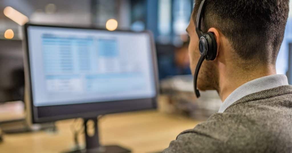 Employé homme portant un casque avec un micro face à son ordinateur