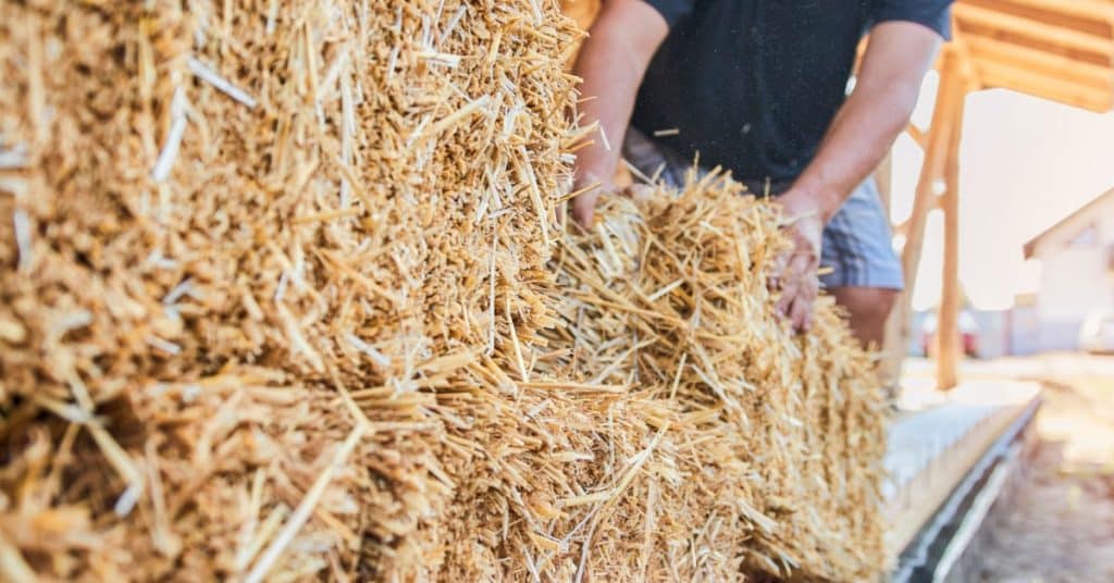 Un homme empile des blocs de paille pour construire un mur de maison 