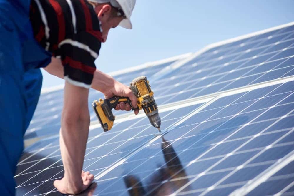 un ouvrier installe des panneaux solaires sur un toit 