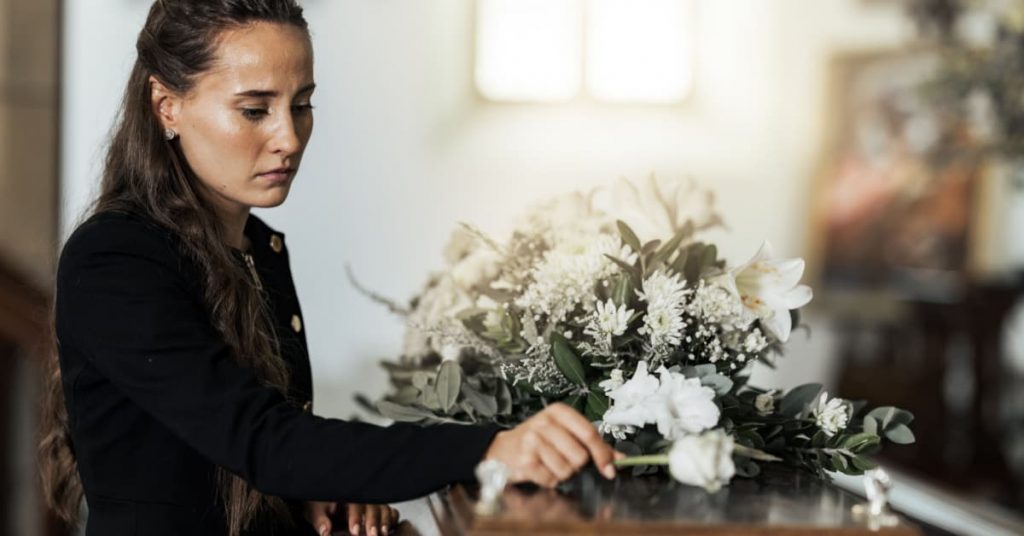 funéraille, jeune femme déposant une rose blanche sur cercueil
