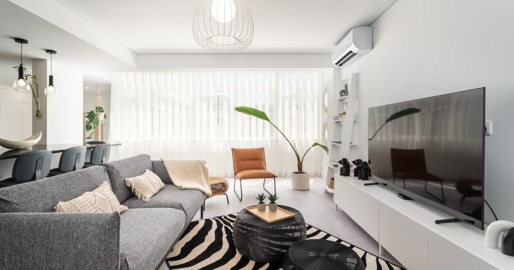Appartement moderne à l'intérieur, salon avec canapé gris et coin télévision et oreillers en crochets sur le canapé.