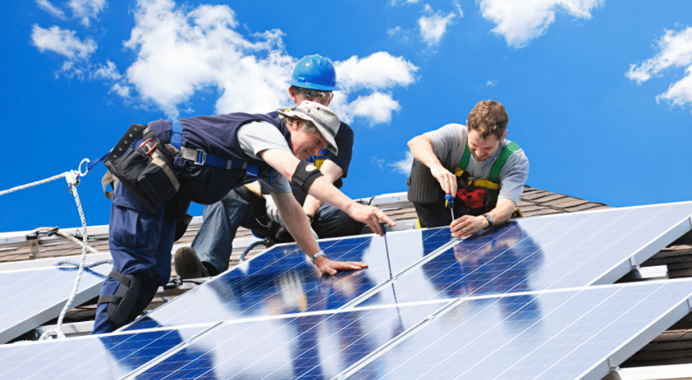 des ouvriers qui installent des panneaux solaires sur le toit d'une maison 