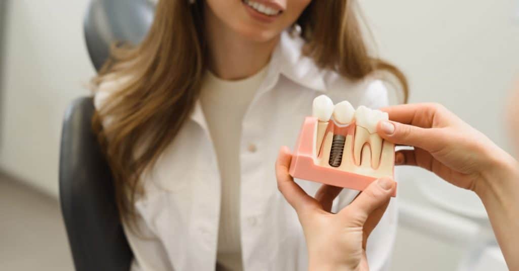 une dentiste explique à une jeune patiente l'intervention de la pose d'implant