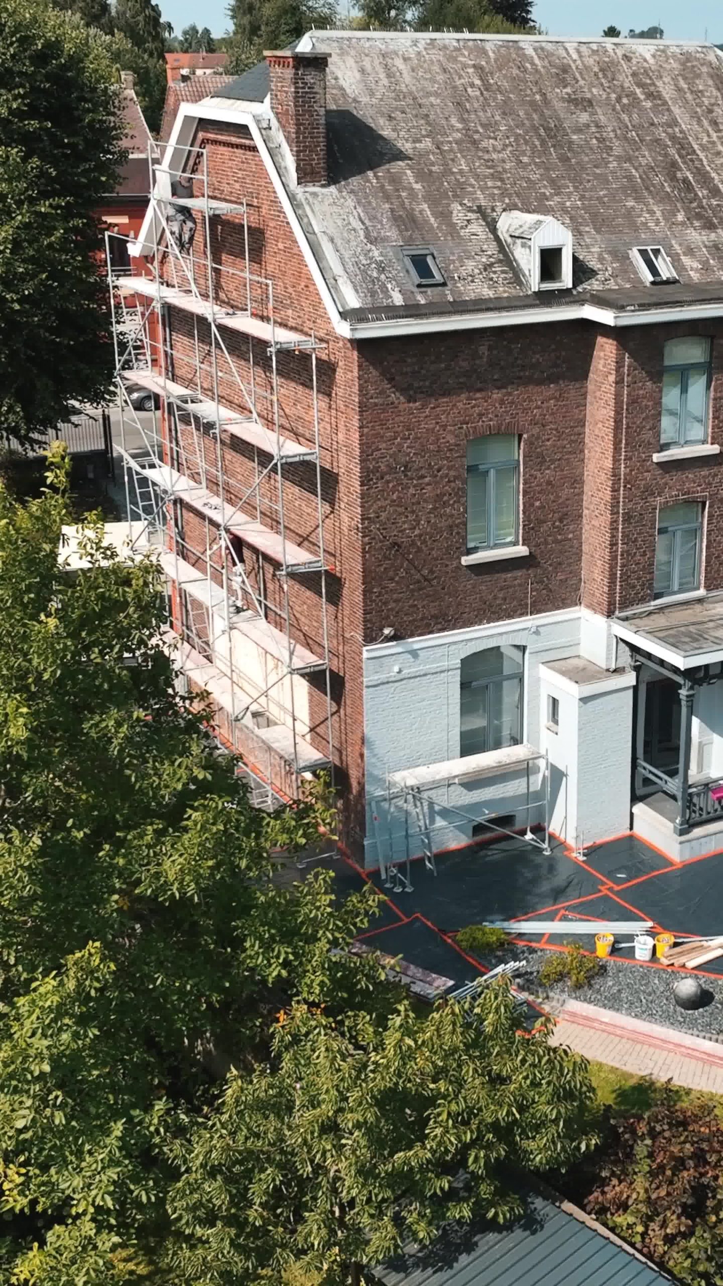 photo d'une maison en brique rouge avec échafaudage en train d'être installé en vue de faire des travaux d'isolation de façade