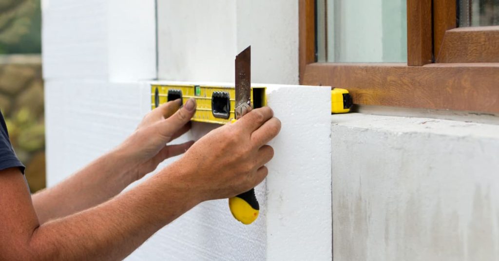 Retouches d'un panneau isolant sur un mur extérieur à l'aide d'un cutter