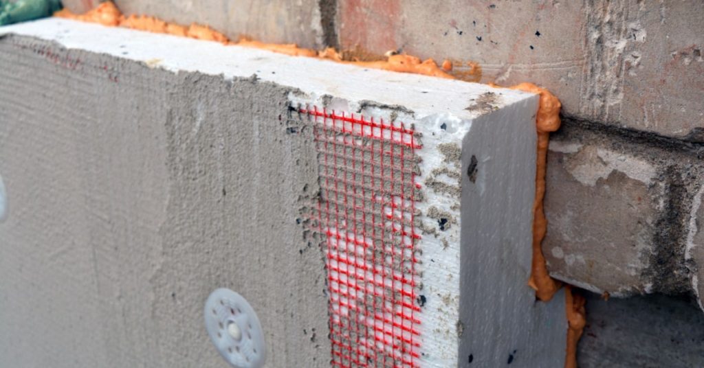 mur en brique d'une façade en train d'être isoler à l'aide d'un isolant sous forme de plaque et d'un enduit