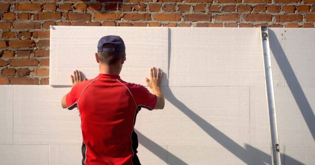 Ouvrier posant une plaque d'isolant sur un mur extérieur