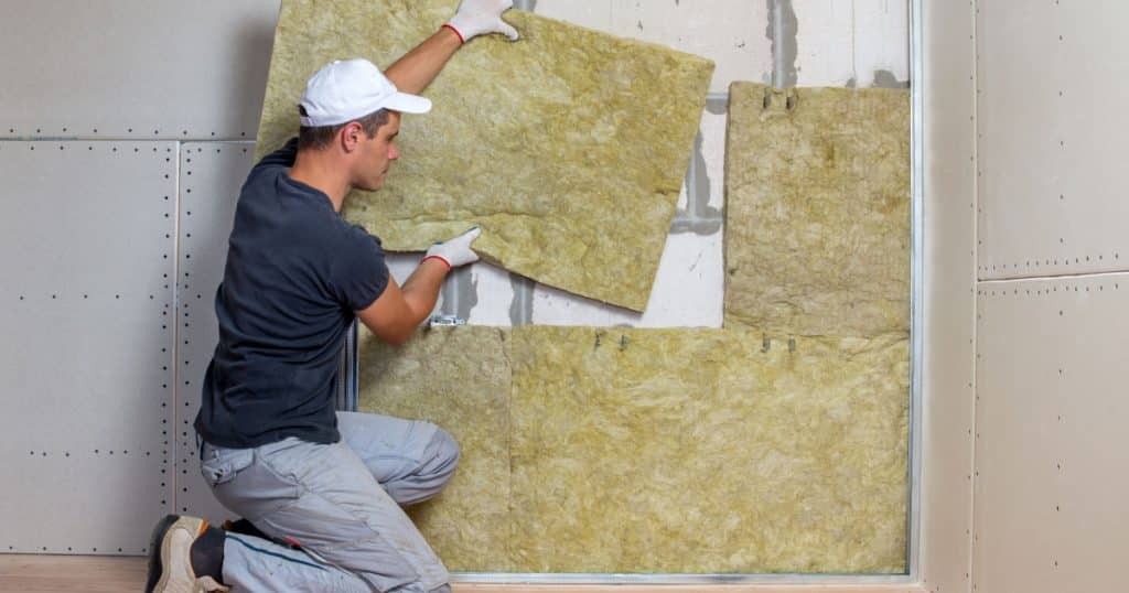 artisan isole un mur intérieur avec laine minérale
