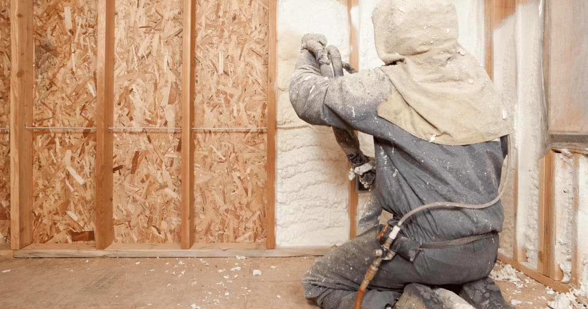 Un homme en train d'isoler un mur intérieur