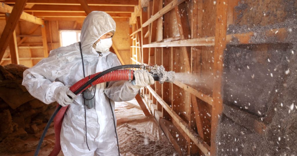 Un homme en combinaison blanche qui réalise une isolation par insufflation
