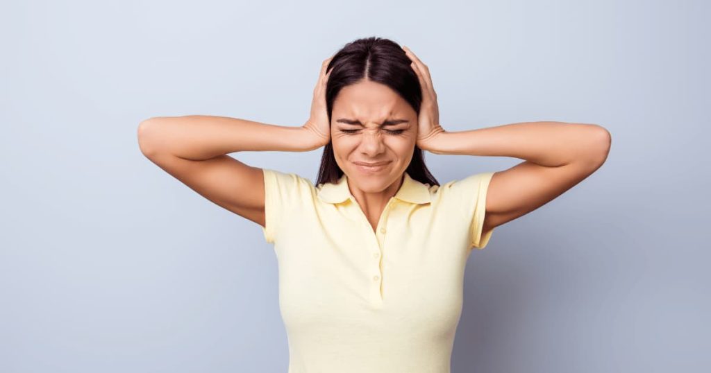 femme qui met ses mains sur ses oreilles 