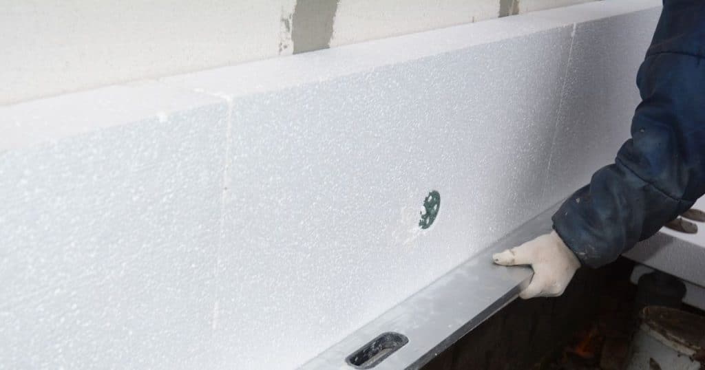 Professionnel en train d'isoler un mur avec des panneaux de polystyrène