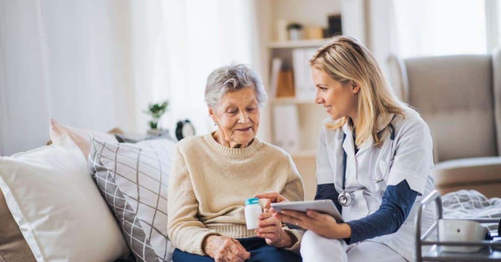 Professionnelle de la santé expliquant la notice d'utilisation d'un médicament à une personne âgée dans une maison de repos et de soins. 