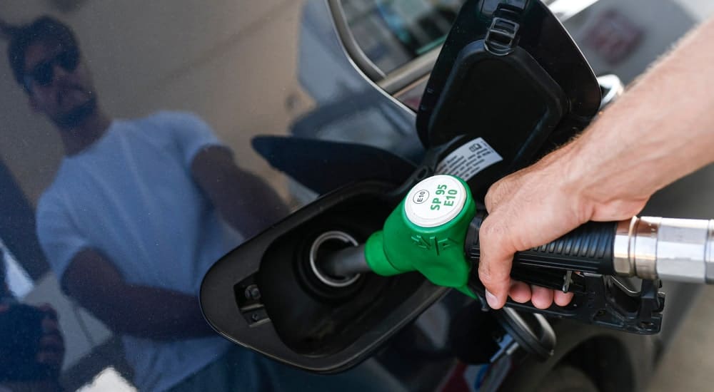Le reflet d'un homme qui met de l'essence dans sa voiture avec sa carte carburant 