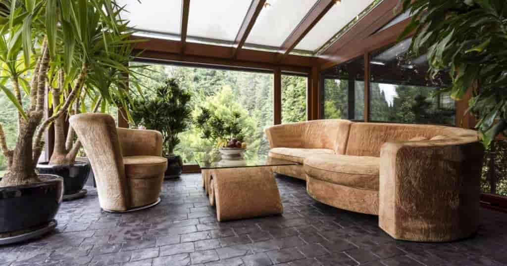 canapé, siège et table en verre modernes dans un salon avec végétation