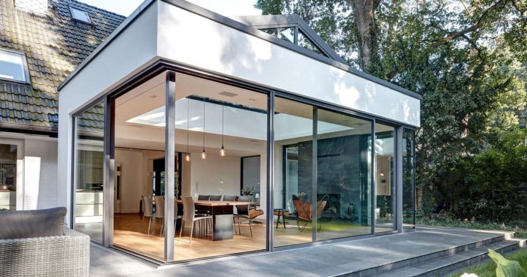 veranda vitrée sous forme de salle à manger avec du mobilier design et épuré qui donne un style élégant à la pièce