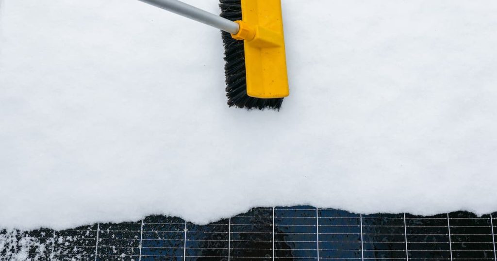 panneau solaire enneigé et brosse pour nettoyage