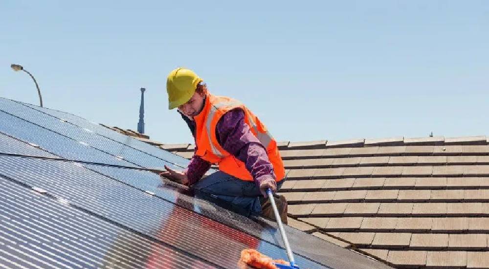 ouvrier en train de nettoyer un panneau solaire