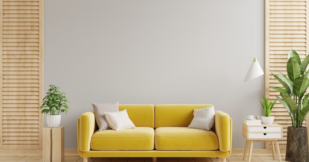 Un divan jaune contre un mur gris