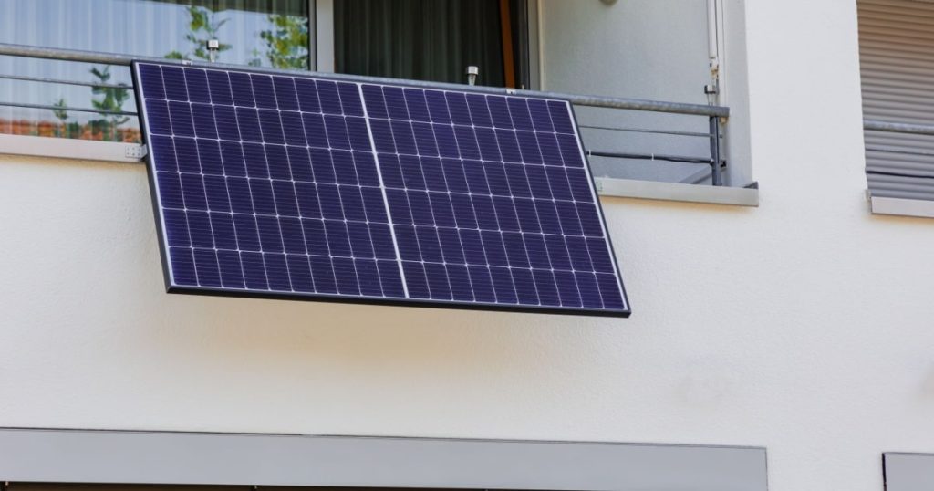 Un panneau solaire installé sur le rebord d'un balcon d'appartement. 
