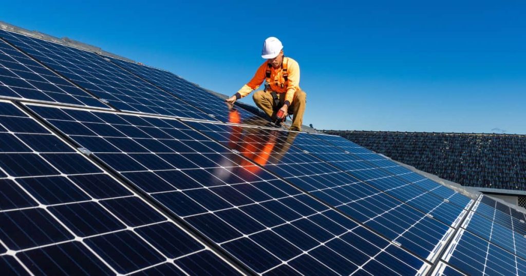 Ouvrier sur un toit s'occupant de panneaux solaires